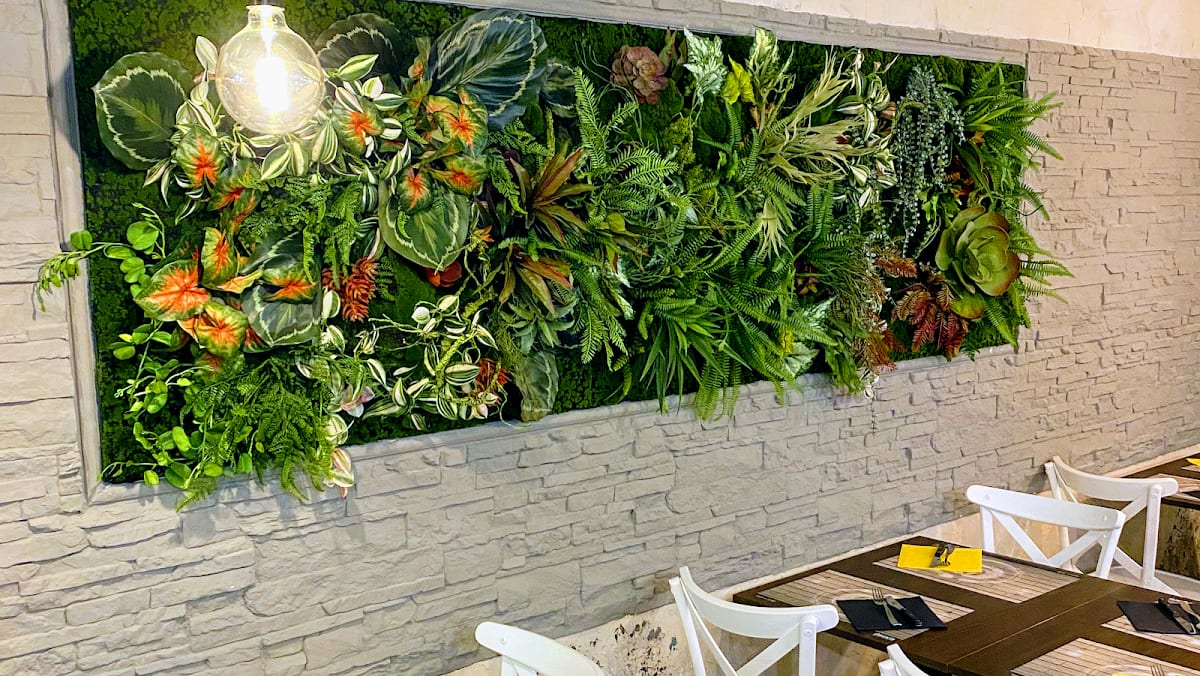 Parete con giardino verticale e tavoli
